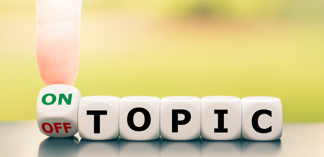 Hand turns a dice and changes the expression "off topic" to "on topic".